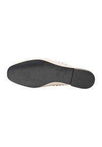 Suola in gomma nera con parte superiore beige liscia. Le caratteristiche di design notevoli includono una texture sottile e il nome del marchio stampato in rilievo sul lato.