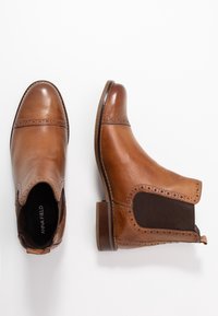 Ruske kožne gležnjače s elastičnim bočnim panelima, ukrasnim čipkastim detaljima i složenim potplatom. Glatka završna obrada s dizajnom zaobljenog prsta.