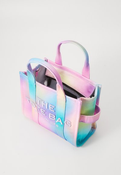 Värviline gradient-totepakk, mis on valmistatud kangast. Omab kaht käepidet, avatud ülaosa, kontrastset siseosa ja esiplaanil on süvistatud tekst.