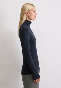 Navy coltrui met lange mouwen en een aansluitend ontwerp. Gemaakt van ribstof, met aansluitende manchetten en een soepele textuur.