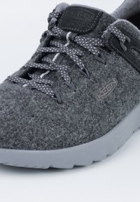 Graue Sneaker aus Textil mit strukturiertem Obermaterial, dunkelgrauen Schnürsenkeln und einer hellgrauen Gummisohle. Mit KEEN-Logo und einem glatten Lederakzent.