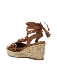 Sandalia cuña marrón con un caja de dedos con estampado de leopardo, diseño con cordones y una entresuela de yute trenzado con detalles texturizados.