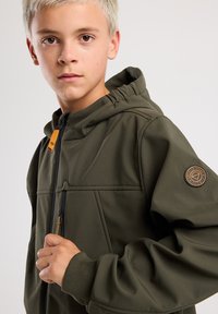 Green hooded jacket with zip closure, featuring a fabric logo patch on the sleeve and textured stitching details throughout.