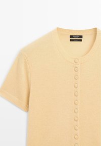 Short-sleeve, light yellow, 100% wool cardigan with a round neck and a row of fabric-covered buttons down the front. Textured knit.
