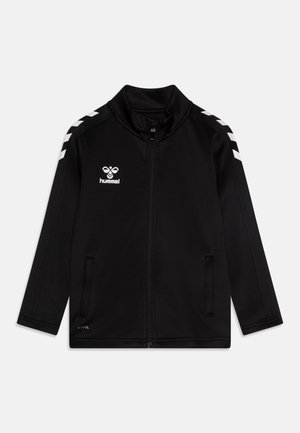 Black zip-up jacket made of smooth material, featuring white chevron accents on shoulders and a logo on the left chest. Two side pockets.