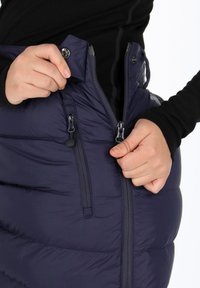 Laikku tummansininen eristyksellä varustettu hame, jossa on vetoketjut ja näkyvät vaakasuorat tikkaukset. Sisältää tiukan vyötärön ja kaksinkertaiset sivutaskut.