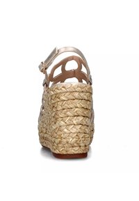 Wedge sandaal met een geweven raffia platform, achterste enkelband met metallic accenten en uitsparingen op de hak. Neutrale kleur.