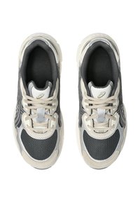 Pari beige, musta ja hopea urheilukengistä, joissa on nauhat, verkkomainen etuosa ja pehmeät pohjat, nähtynä ylhäältä valkoista taustaa vasten.