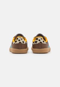 Brown sneakers with a textured finish, featuring a blue side panel and a colorful leopard print on the heel. Rubber sole with grip.