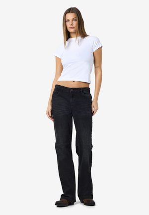 Zwarte denim jeans met een rechte pijp, vijf zakken en een knoopsluiting. Gecombineerd met een witte, cropped t-shirt met korte mouwen.