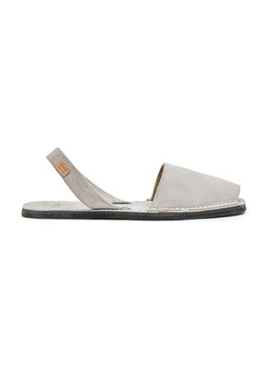 Sandalia slingback de ante gris claro con puntera cerrada, suela plana negra y detalles cosidos sobre un fondo blanco.