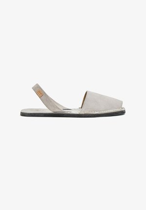 Sandalia slingback de ante gris claro con puntera cerrada, suela plana negra y detalles cosidos sobre un fondo blanco.