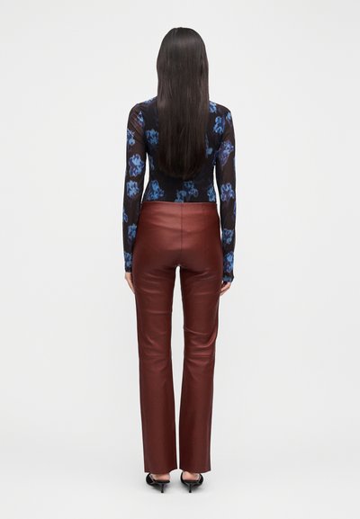 Long burgundy leather pants paired with a black floral long-sleeve top. The top features a sheer texture and blue floral pattern.