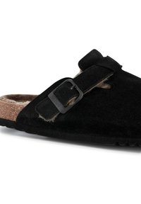Svart mockasandal i slip-on-design med kork-mellansula, justerbar rem med svart spänne och mjukt foder för komfort. Texturerad gummisul.