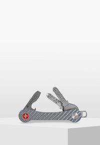 Multiverktyg med handtag i grå kolfiber, flera verktyg av rostfritt stål och en röd Schweizisk korssymbol. Kompakt och funktionell design.