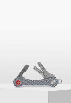 Multi-tool featuring a grey carbon fiber handle, multiple stainless steel tools, and a red Swiss cross emblem. Compact and functional design.