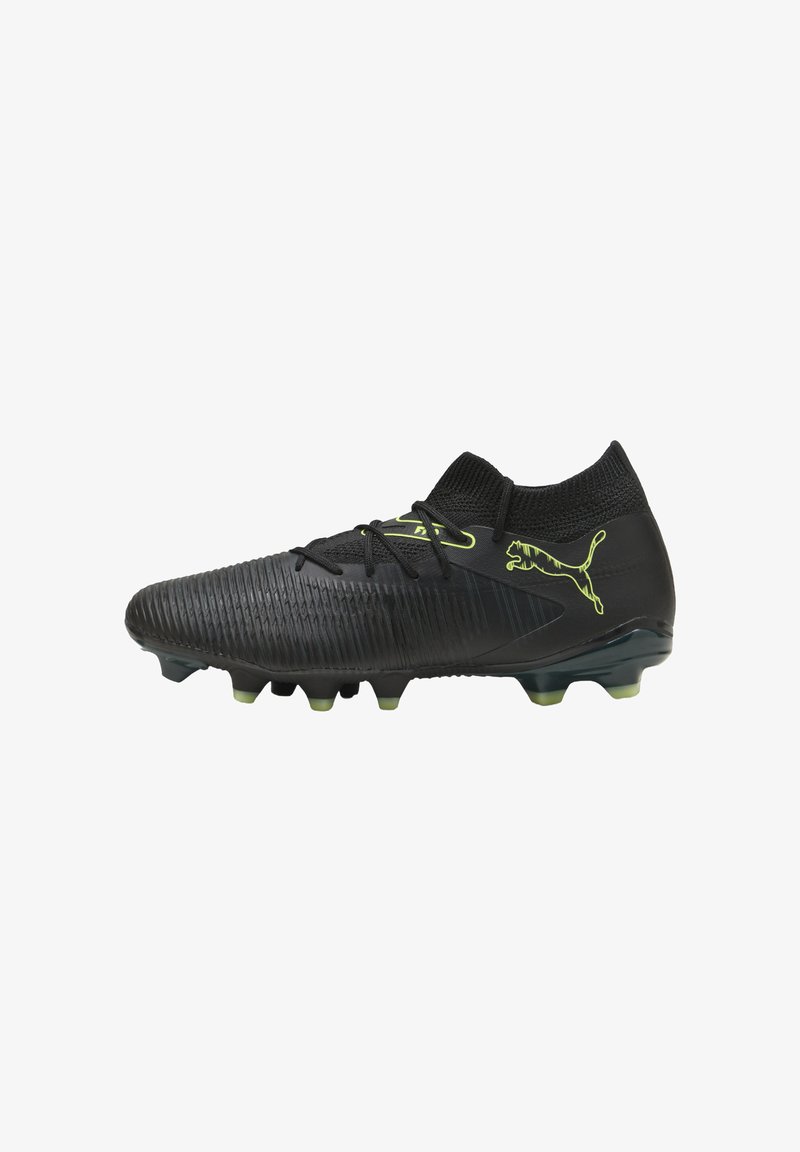 Botín de fútbol negro con parte superior texturizada, cuello de punto y acentos en verde lima. Cuenta con una suela con tacos para tracción en superficies de hierba.