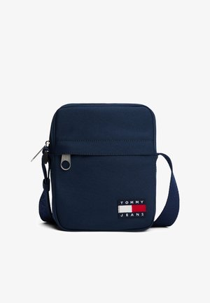 Granatowa torba na ramię z przednią kieszenią na zamek i naszywką z logo Tommy Jeans, z regulowanym paskiem na ramię.