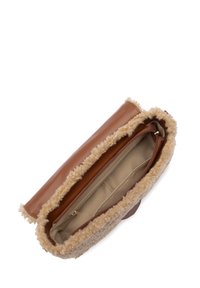 Sac en cuir marron avec une bordure en fausse fourrure beige. La fermeture éclair ouverte révèle un intérieur beige avec une poche zippée et plusieurs compartiments pour l'organisation.