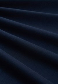 Donker marineblauw stof met een gladde textuur, voorzien van zachte plooien en een subtiele glans. Het materiaal lijkt lichtgewicht en veelzijdig.