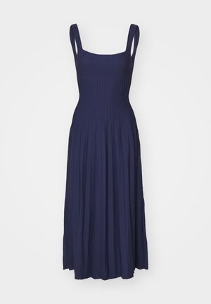 Robe maxi bleu marine avec un corsage côtelé et une jupe plissée. Caractéristiques des bretelles larges et une taille cintrée, fabriquée dans un tissu doux et extensible.