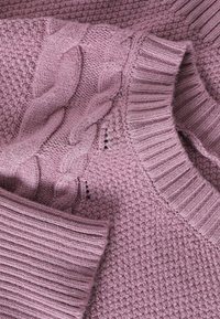 Svijetlopurple pleteni pulover s teksturiranim završetkom, detaljima od pletenih kablova i rebrastim ovratnikom i manžetama. Mekani, udobni materijal.