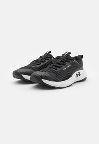 Zwarte mesh sportchoenen met een gestructureerde bovenkant, witte zoolaccenten, platte veters en branding op de zijkant en tong.