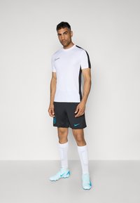 Valge lühikeste varrukatega särk mustade aktsentidega, mustad lühikesed püksid, valged sokid ja helesinised spordijalatsid. Esindab Nike brändi ja meeskonna logo.