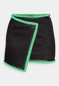 Jupe asymétrique noire avec bordure en polaire vert vif et un seul bouton noir sur la fermeture à rabat avant.