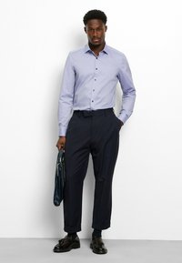 Light purple striped button-up shirt, dark navy tailored trousers, and black dress shoes. Holding a dark blue folder. Simple, clean design.