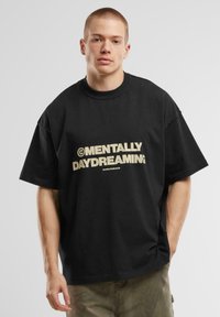 Juodas per didelis 100% medvilnės marškinėliai, su ryškiu auksiniu grafiniu užrašu „MENTALLY DAYDREAMING“ priekyje. Trumpomis rankovėmis.