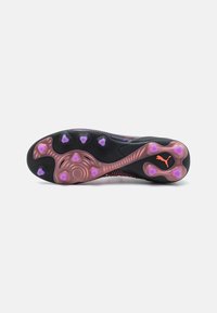 Black athletic shoe sole with pink and purple traction studs, textured surface, distinctive Puma logo, and a dynamic design.