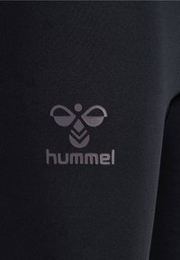 Leggings atletici neri realizzati in tessuto elasticizzato, con il logo argento "hummel" e un design distintivo con un motivo a ape.