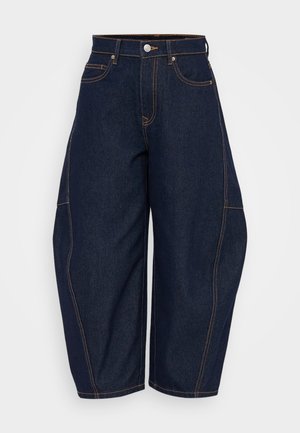 Jeans de mezclilla de corte ancho en azul oscuro con cintura alta, costuras naranjas en contraste y bolsillos frontales. Cuenta con un cierre de botón y pasadores para cinturón.