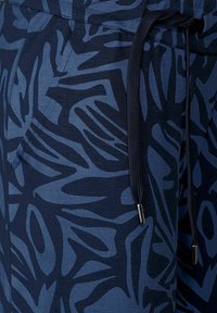 Marinblå joggingbyxor med ett abstrakt mönster i mörkblått, elastisk midja med dragsko och sidofickor. Mjukt tyg.