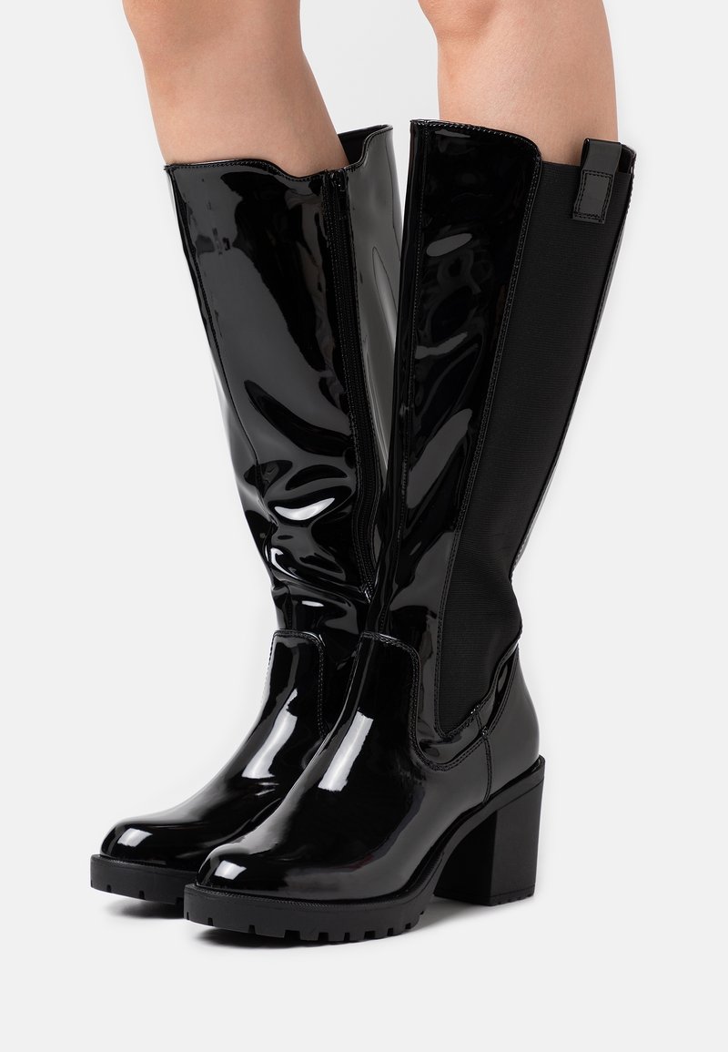Bottes noires montant jusqu'aux genoux avec une finition en cuir verni brillant, dotées d'une fermeture éclair à l'arrière, d'un talon carré et de panneaux latéraux élastiques pour un ajustement parfait.