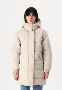 Manteau doudoune beige avec un col montant et une capuche ajustable. Présente des poignets élastiques et des poches latérales. Design matelassé horizontal sur l'ensemble.