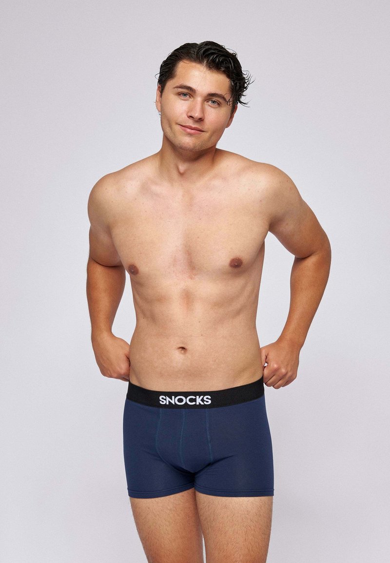 Boxer-briefs navy avec une taille noire comportant le nom de la marque "SNOCKS" en blanc. Texture lisse et coupe ajustée, conçues pour le confort.