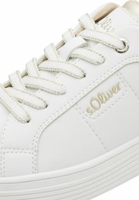 Weiße Sneaker aus strukturiertem Synthetikmaterial, mit goldenen Akzenten, runden Schnürsenkeln und einem geprägten Logo-Detail an der Seite.