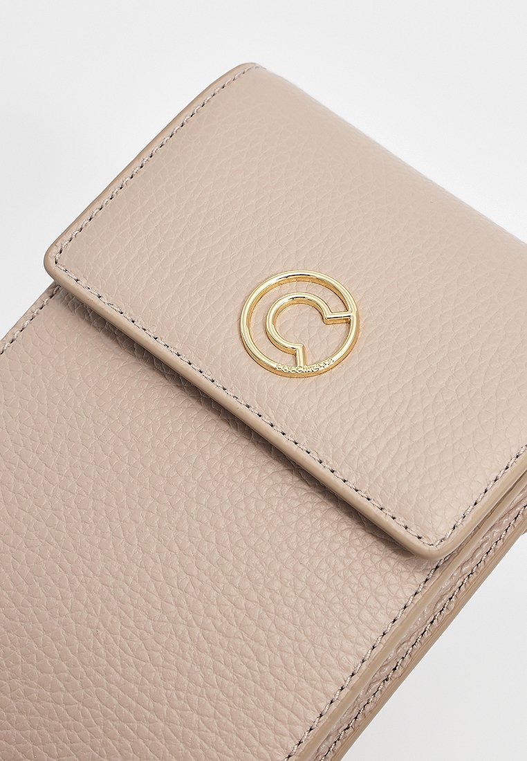 Beige Leder-Wallet mit strukturierter Oberfläche, ausgestattet mit einem goldenen, runden Logo und einem Klappverschluss mit sichtbaren Steppnähten.