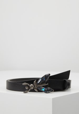 Ceinture noire texturée avec une boucle décorative en forme d'insecte présentant des accents bleu foncé et argentés semblables à des gemmes, exposée sur une surface blanche.