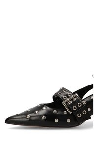 Zapato de piel negro con punta afilada, adornado con tachuelas plateadas y una correa ancha que presenta una gran hebilla plateada.