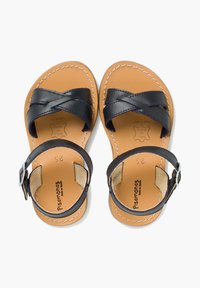 Tummansiniset nahka-sandaalit, joissa on ristiin menevät hihnat ja säädettävä nilkkasolki. Vaaleanruskea nahkasisus valkoisella ompelella. Koko 23 merkitty sisäpuolelle.