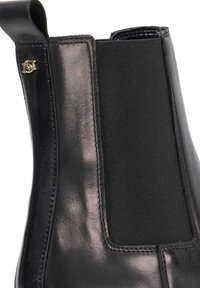 Black leather ankle boot with elastic side panels, smooth texture, stitched detailing, and a gold logo accent on the outer side.