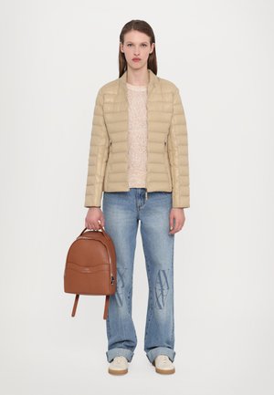 Giacca a vento beige, maglione leggero a maglia, jeans blu con motivi, zaino marrone e scarpe beige. Texture morbide e design informale.