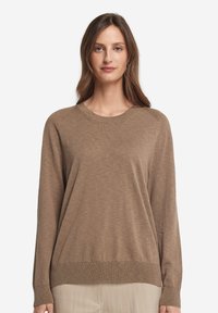 Ljusbrun långärmad tröja med rund halsringning, mjuk textur och ribbade manschetter och fåll. Har en avslappnad passform.