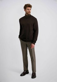 Brauner Rollkragenpullover kombiniert mit hellgrauen Hosen und dunkelbraunen Slippers. Glatte Textur, tailliertes Design und subtile tonale Variationen.