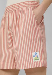 Katoenen shorts met verticale roze en crèmekleurige strepen, voorzien van een elastische tailleband, zijzakken en een decoratieve logopatch.