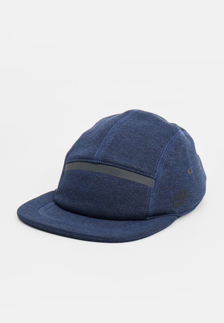 Gorra azul con visera plana, hecha de tela texturizada. Cuenta con una franja reflectante gris y un logo negro en el lateral. Diseño de cuatro paneles.