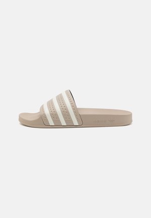 Beżowa sandałka typu klapek Adidas z białymi paskami na pasku i teksturowaną podeszwą, zaprojektowana do codziennego użytku.